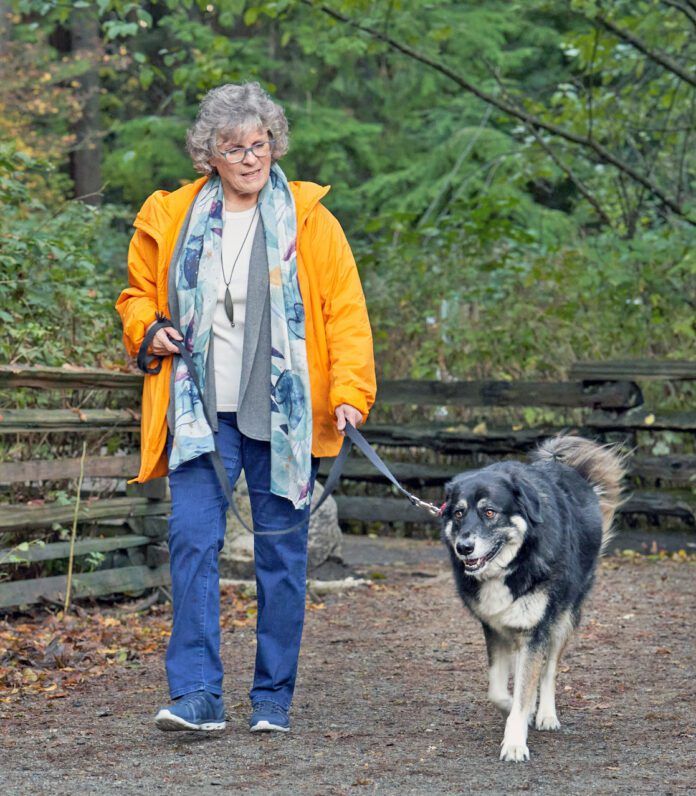 Woman taking her dog for a walk on a forest path Woman taking her dog for a walk on a forest path
