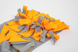 Orange and gray handmade felt snuffle mat unfolded on white background, pet dog enrichment toy product flatlay concept